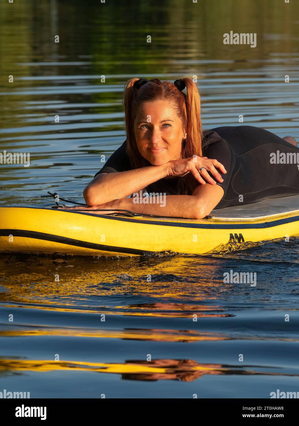 Frau, die entspannt auf dem Stand-up-Paddle-Board im See liegt Stockfoto