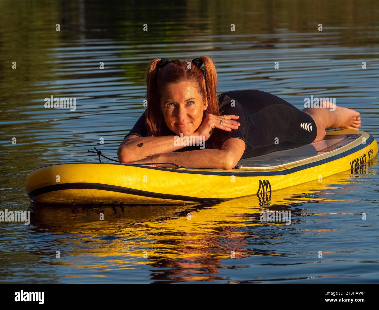 Frau, die entspannt auf dem Stand-up-Paddle-Board im See liegt Stockfoto
