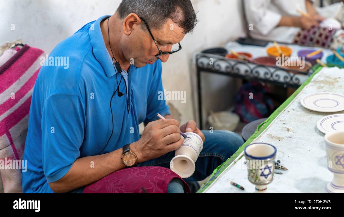 Fes, Marokko - 10. September 2022: Handwerker malen und dekorieren farbenfrohe Keramikprodukte in der Töpferei Stockfoto