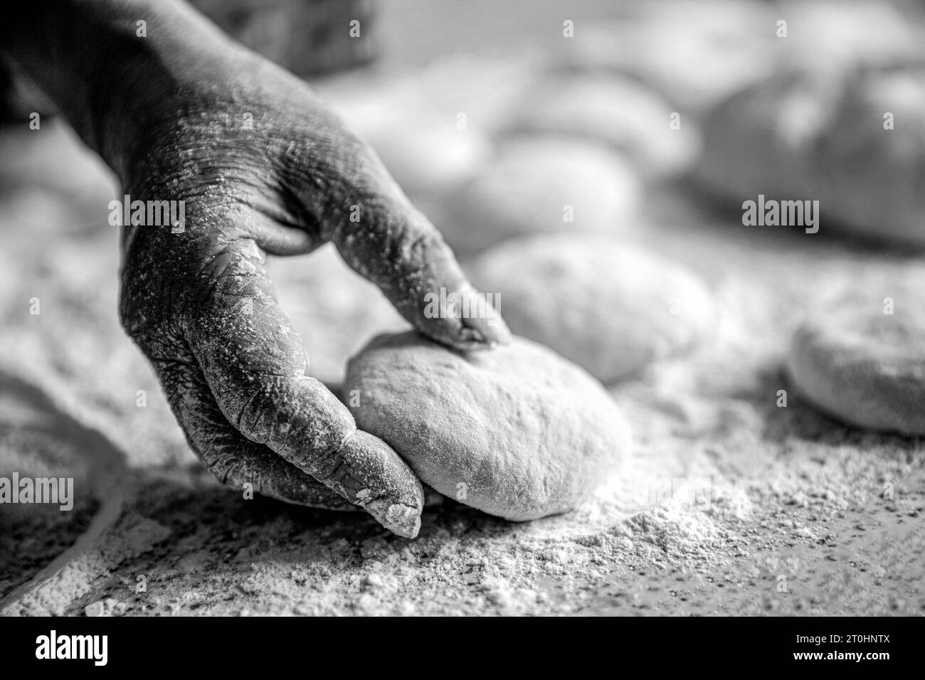 Frauenhände Rollen Teig für Kuchen. Backen zu Hause. Hausgemachter Kuchen-Teig in den Händen der Frauen. Prozess der Tortenherstellung. Schwarz-weiß Stockfoto