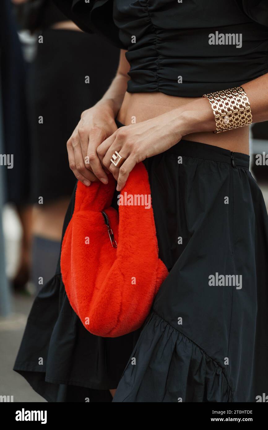 Modedetails: Armband, schwarzes Oberteil und Rock, rote flauschige Tasche, gesehen außerhalb der PRADA Show während der Mailand Fashion Week Damenmode Frühjahr/Sommer 2024. Stockfoto