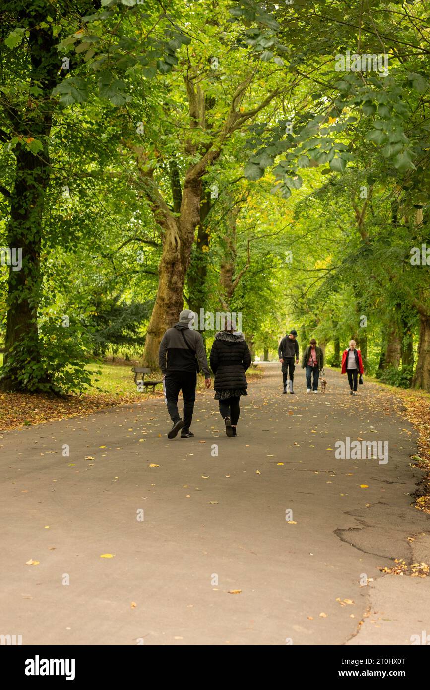 Leute, die im Oktober im Roundhay Park, Leeds, West Yorkshire, Großbritannien, spazieren gehen Stockfoto
