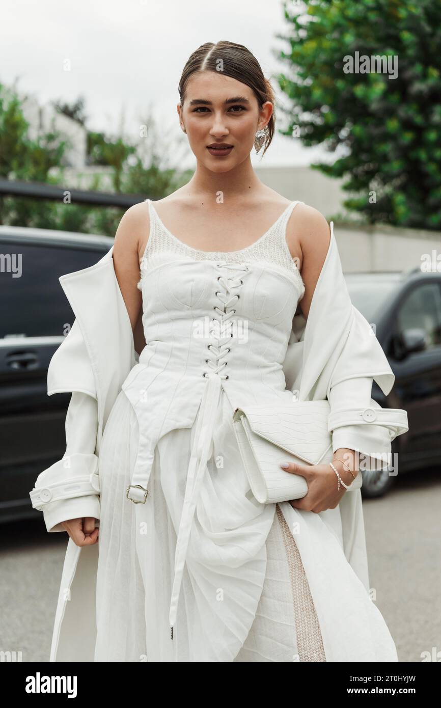 Ein Gast trägt weißes Kleid, Mantel und Tasche, das vor der PRADA-Show während der Mailänder Fashion Week im Frühjahr/Sommer 2024 zu sehen ist. Stockfoto