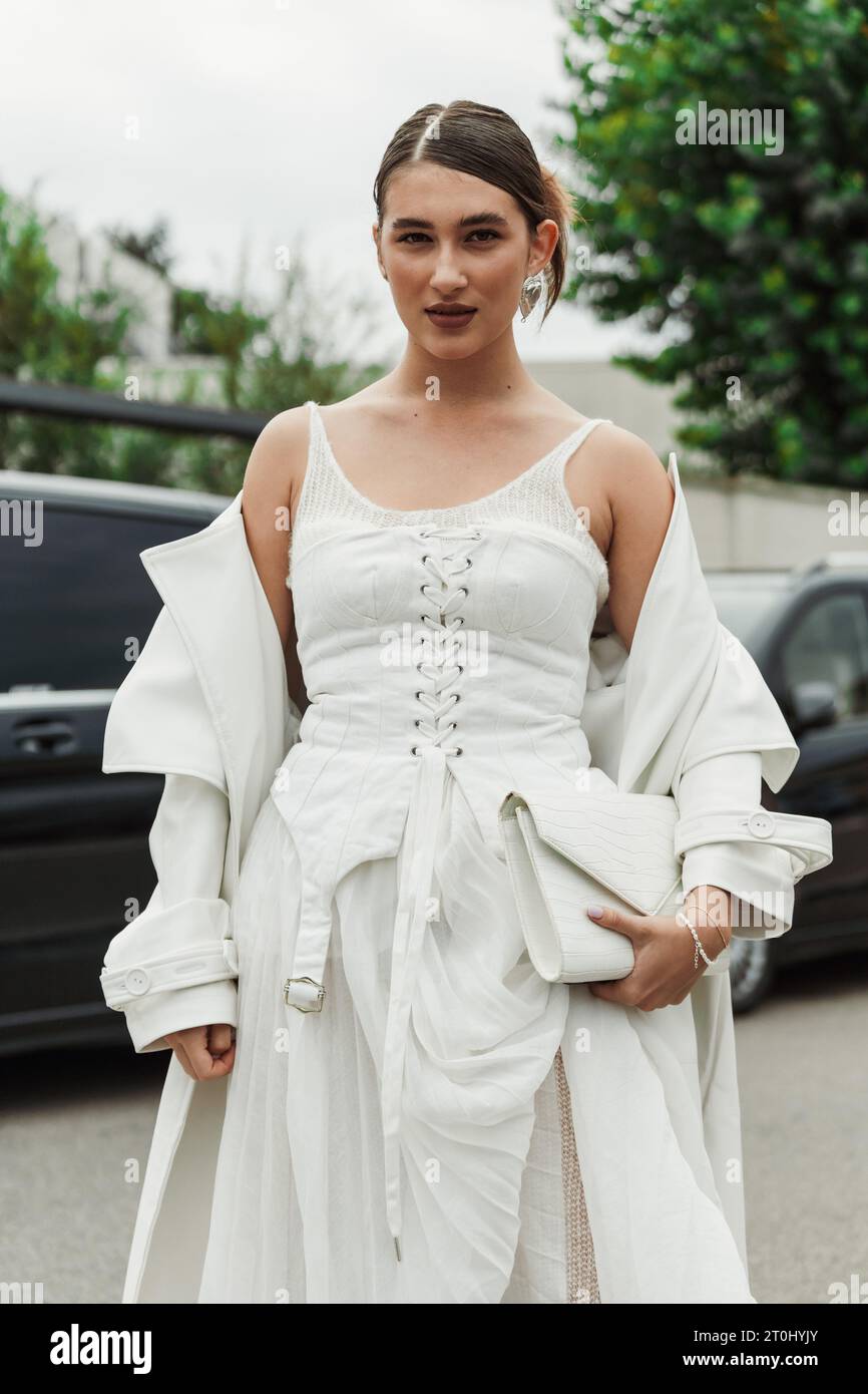 Ein Gast trägt weißes Kleid, Mantel und Tasche, das vor der PRADA-Show während der Mailänder Fashion Week im Frühjahr/Sommer 2024 zu sehen ist. Stockfoto