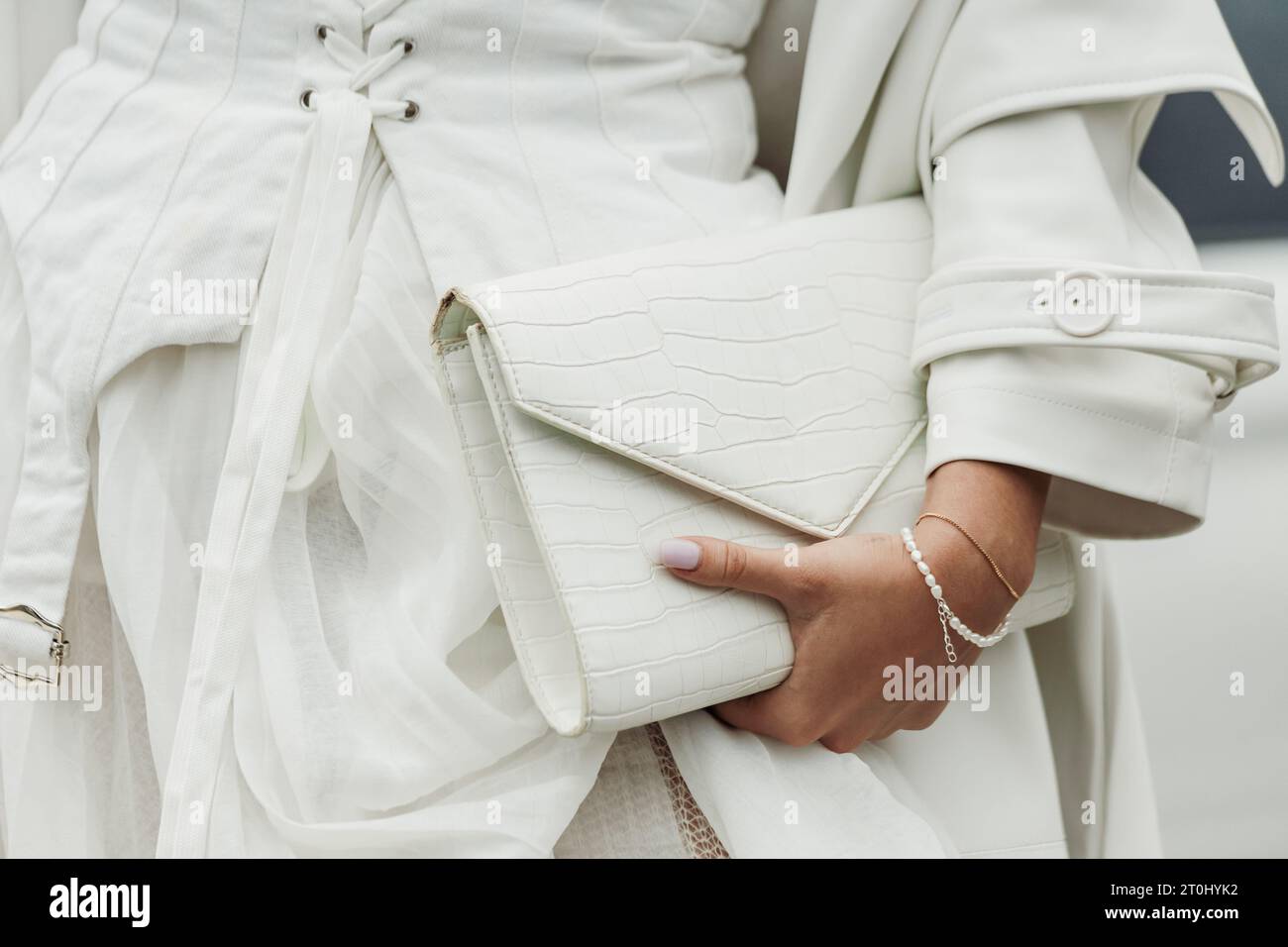 Ein Gast trägt weißes Kleid, Mantel und Tasche, das vor der PRADA-Show während der Mailänder Fashion Week im Frühjahr/Sommer 2024 zu sehen ist. Stockfoto