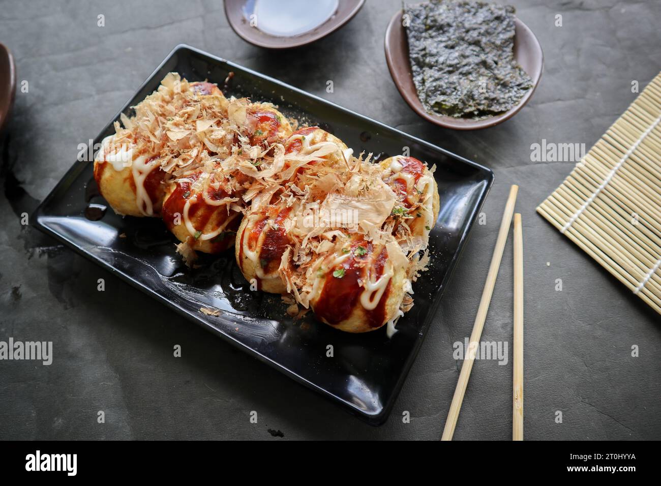 Takoyaki ist ein japanisches Essen, das aus Weizenmehlteig, Oktopusfleisch oder anderen Füllungen hergestellt wird, serviert mit Sauce, Mayonnaise und Topping in Form von Ka Stockfoto