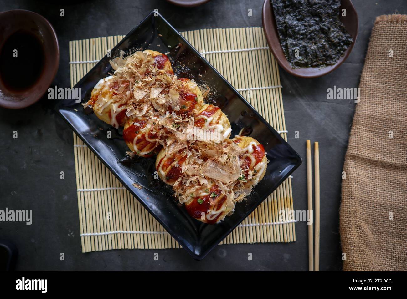 Takoyaki ist ein japanisches Essen, das aus Weizenmehlteig, Oktopusfleisch oder anderen Füllungen hergestellt wird, serviert mit Sauce, Mayonnaise und Topping in Form von Ka Stockfoto