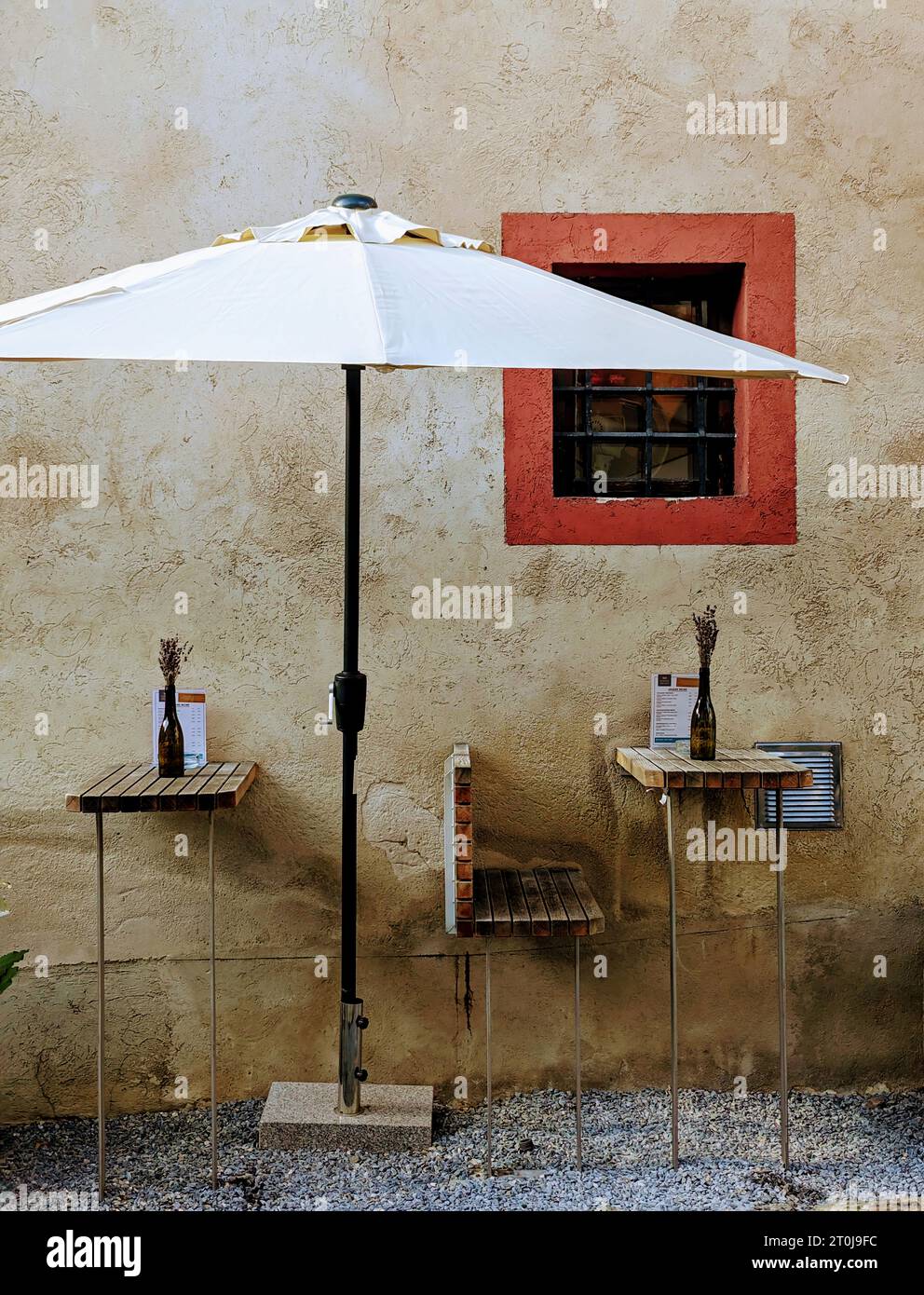 Ein Flair der europäischen Kaffeekultur! Einfache Sitzplätze in einem schattigen Sonnenschirm, die den köstlichen Geschmack erlesener Weine und lokaler Köstlichkeiten versprechen. Stockfoto