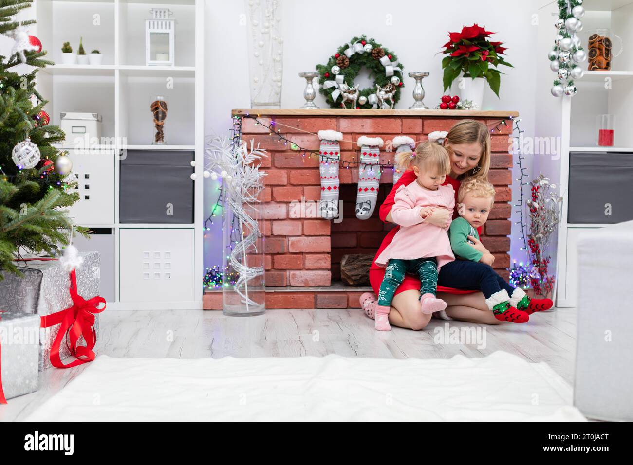 Die liebende Mutter hält ihre Tochter und ihren Sohn auf ihrem Schoß Stockfoto