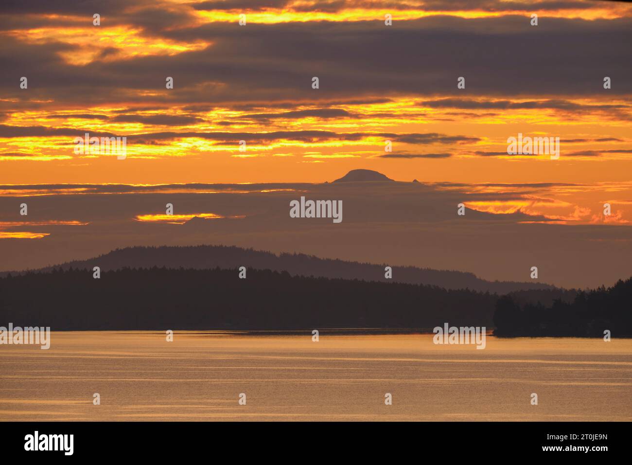 Vor Sonnenaufgang war ein wunderschöner orangener Himmel voller Wolken und der 130 km entfernte Mt. Baker über dem Wasser von Vancouver Island aus zu sehen. Stockfoto