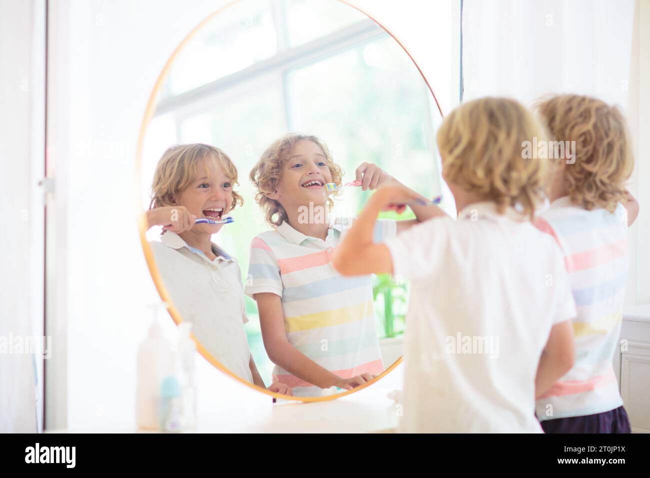 Kinder im Badezimmer putzen die Zähne und schauen in den Spiegel. Kleiner Junge mit Zahnbürste und Zahnpasta. Zahnpflege und Mundhygiene. Stockfoto