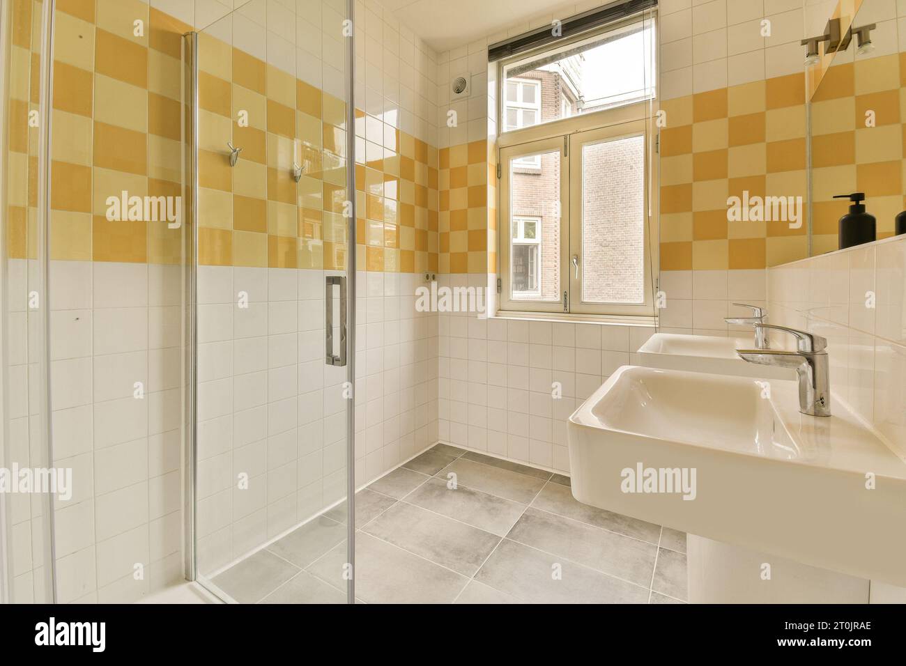 Ein Badezimmer mit gelben und weißen Fliesen an den Wänden, Duschkabine und Waschbecken sind ebenfalls auf diesem Bild zu sehen Stockfoto