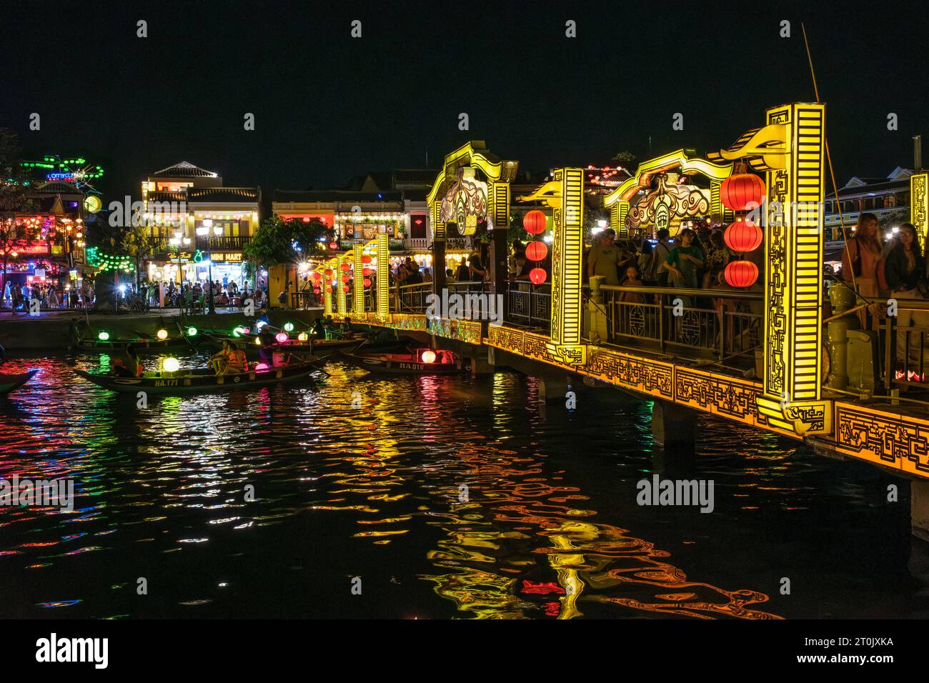 Hoi An, Vietnam. Fußgängerbrücke und Touristenboote auf dem Fluss Thu Bon bei Nacht. Stockfoto