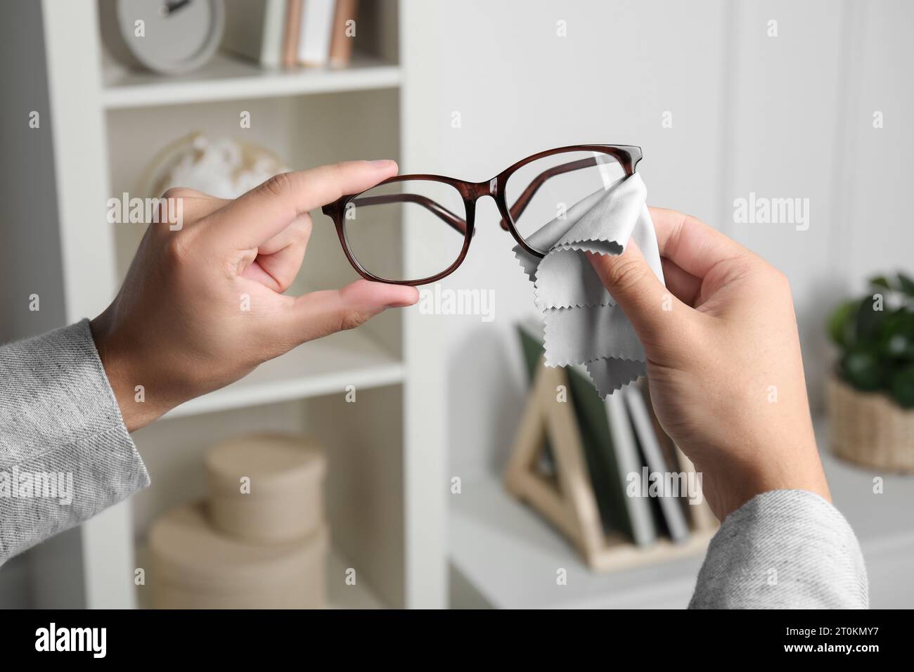 Mann, der drinnen Gläser mit Mikrofasertuch abwischt, Nahaufnahme Stockfoto