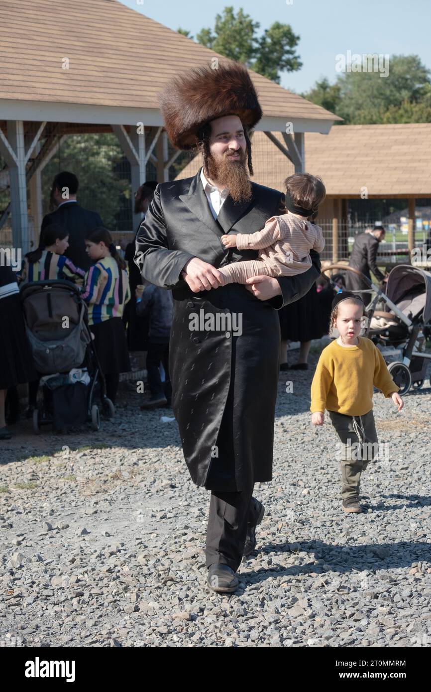 Ein chassidischer Vater mit langem gelocktem Peyot und einem Schtreimel-Pelzhut geht mit seinem Kind. In Monsey, New York Stockfoto
