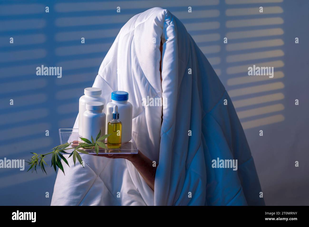 Finden Sie Ruhe: Mädchen kämpft Schlaflosigkeit unter Trusty Blanket mit Schlaffkapsel mit einem Cannabiszweig der Nachtstation mit Blinden Stockfoto