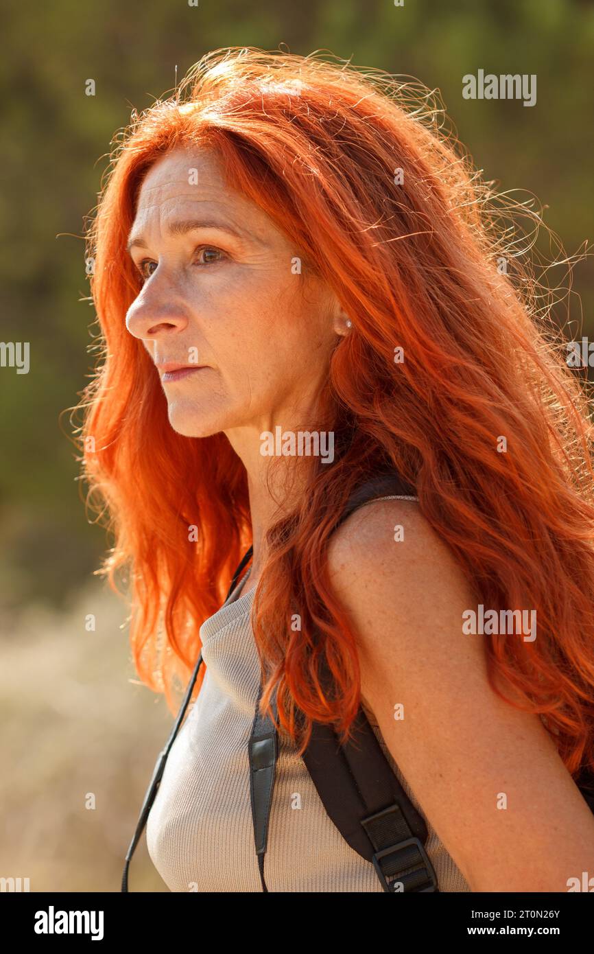 Reife rothaarige Frau, die im Wald von Arenales del Sol, Spanien, wegschaut Stockfoto