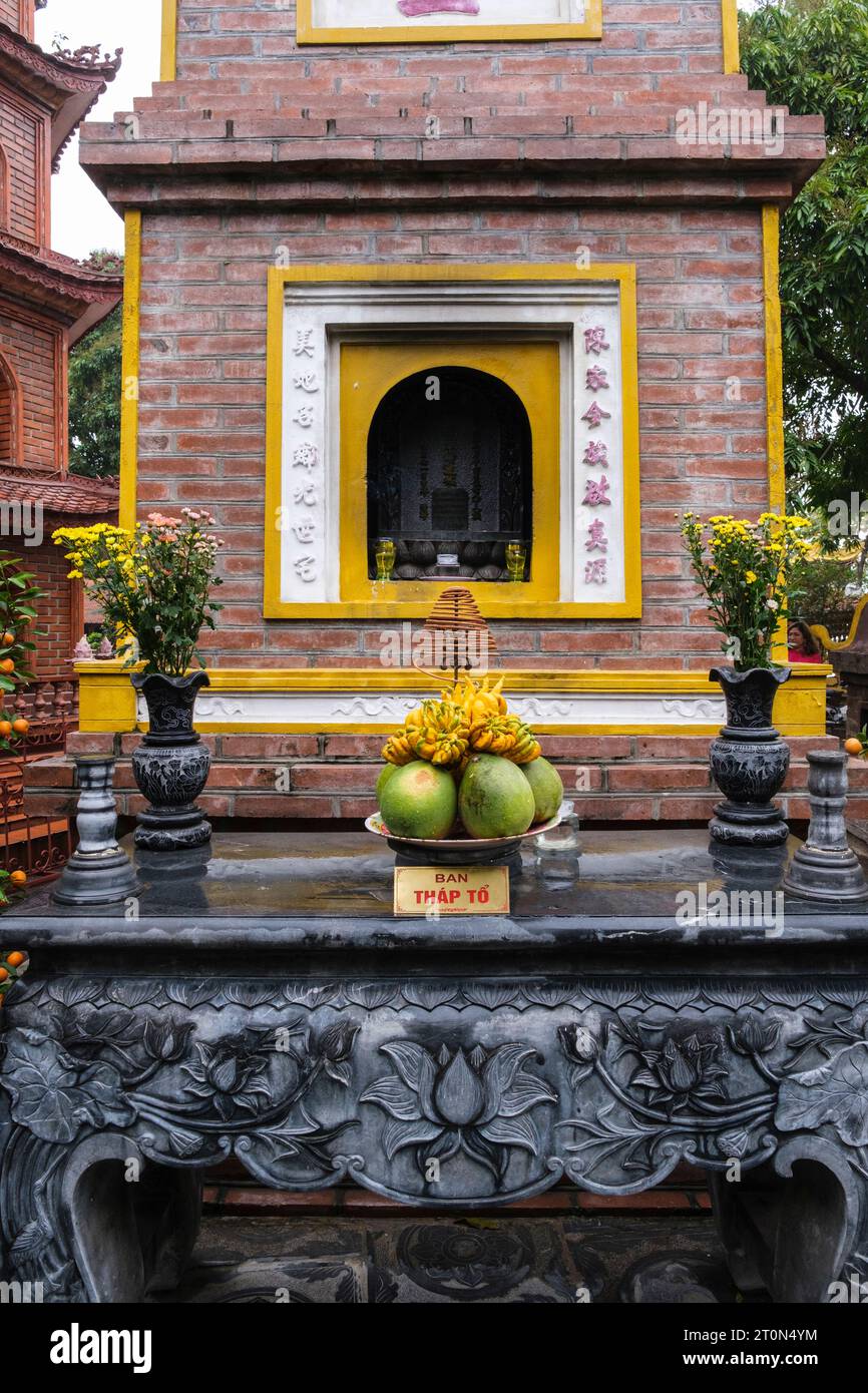 Hanoi, Vietnam. Tran Quoc Pagode, der älteste buddhistische Tempel in Hanoi. Opfergaben vor dem Schrein in der Pagodennische. Stockfoto