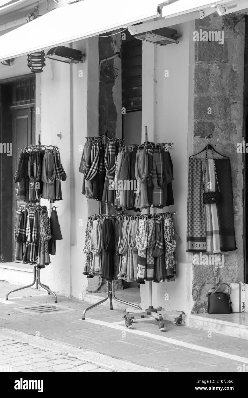 Schals hängen an einem zweilagigen runden Kleiderständer, der in den Geschäften der Altstadt von Rhodos in Schwarz-weiß ausgestellt wird Stockfoto