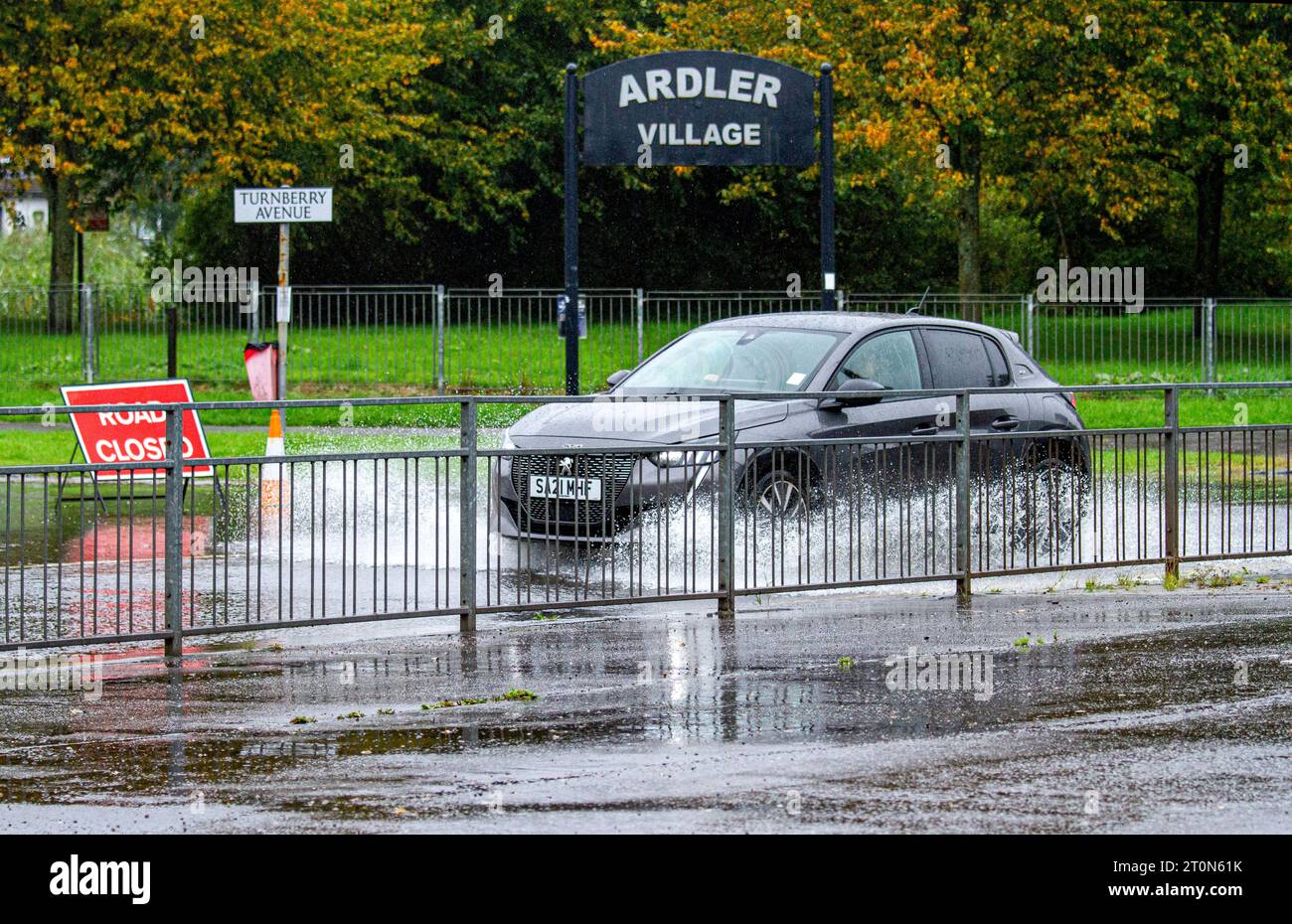 Dundee, Tayside, Schottland, Großbritannien. Oktober 2023. Wetter in Großbritannien: Die Überschwemmungen auf der MacAlpine Road in Ardler Village sind das Ergebnis von nächtlichen sintflutartigen Regenfällen in Dundee. Regen hat die Reise in Dundee beeinflusst und einige Busse aufgrund überfluteter Straßen gezwungen, umzuleiten. Autofahrer werden durch überflutete Straßen gefahren, wodurch Wasser außergewöhnlich hoch spritzt. Quelle: Dundee Photographics/Alamy Live News Stockfoto