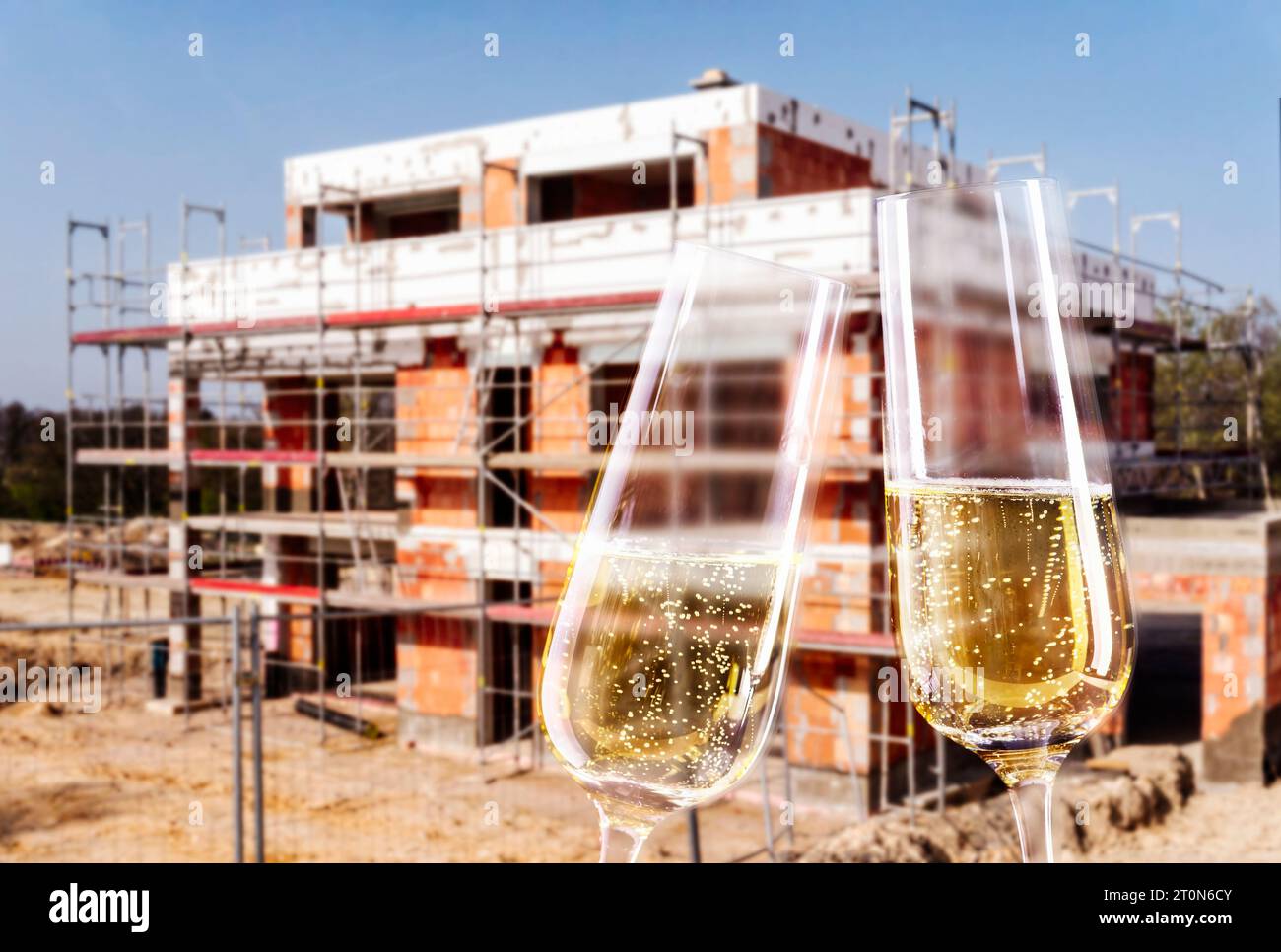 Sektgläser und Baustelle mit der Hülle eines Familienhauses Stockfoto