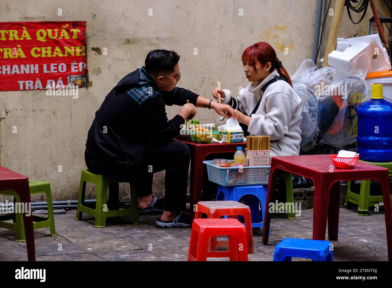 Hanoi, Vietnam. Ein Paar, das an einem Fastfood-Stand auf dem Bürgersteig zu Mittag isst. Stockfoto