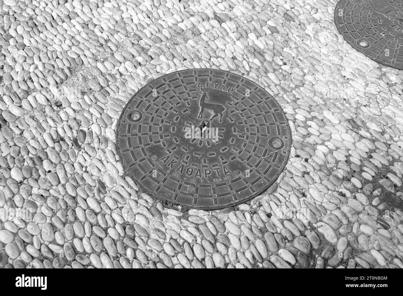 Runder Mannlochdeckel, eine abnehmbare Platte, die eine Öffnung im Boden bedeckt, entworfen für die Akropolis von Rhodos in Schwarz-weiß Stockfoto