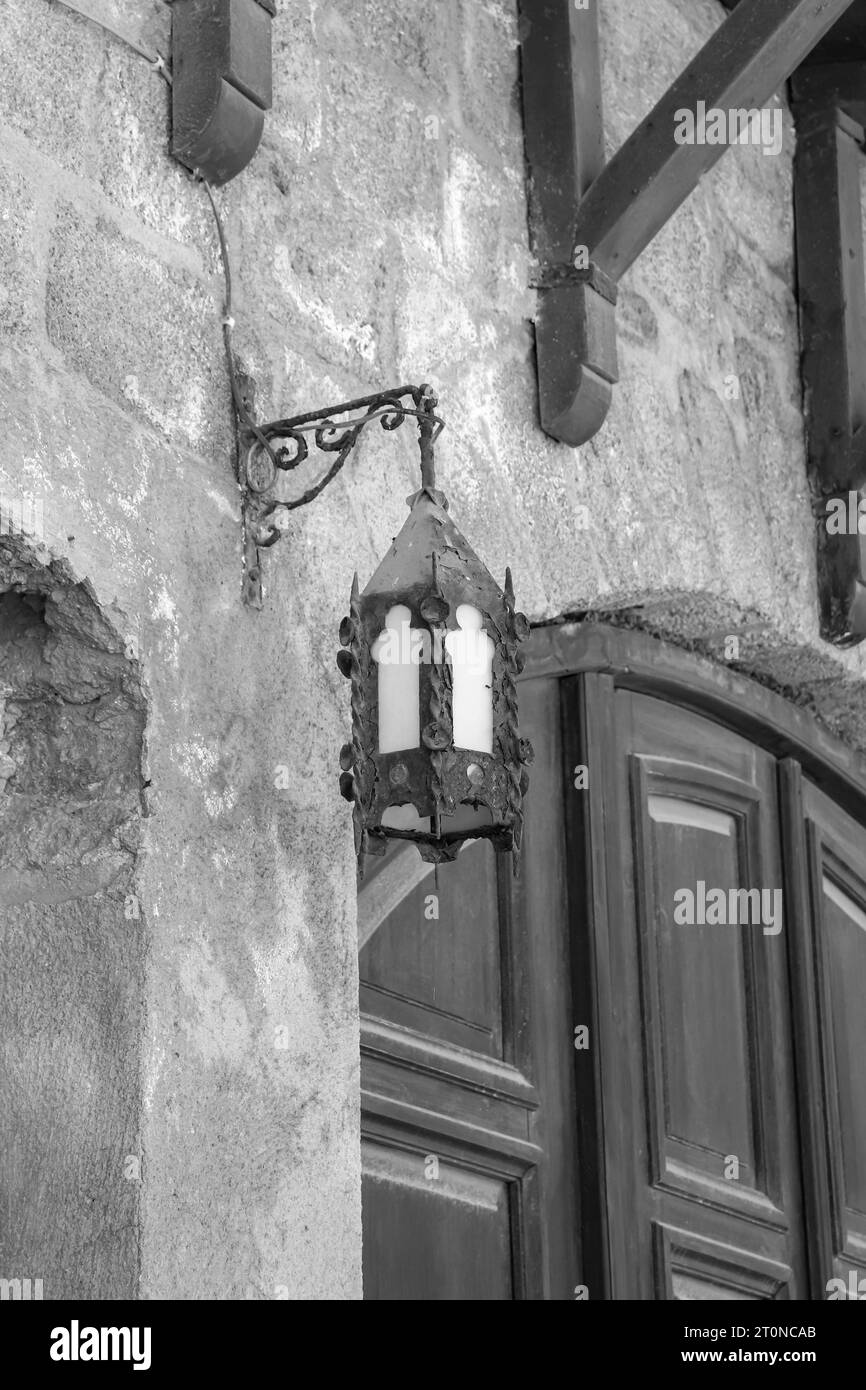 Schwarz-weiße, antike, mittelalterliche Metalllampe im Vintage-Stil, die an der Seite einer Ziegelmauer in der Altstadt von Rhodos hängt Stockfoto
