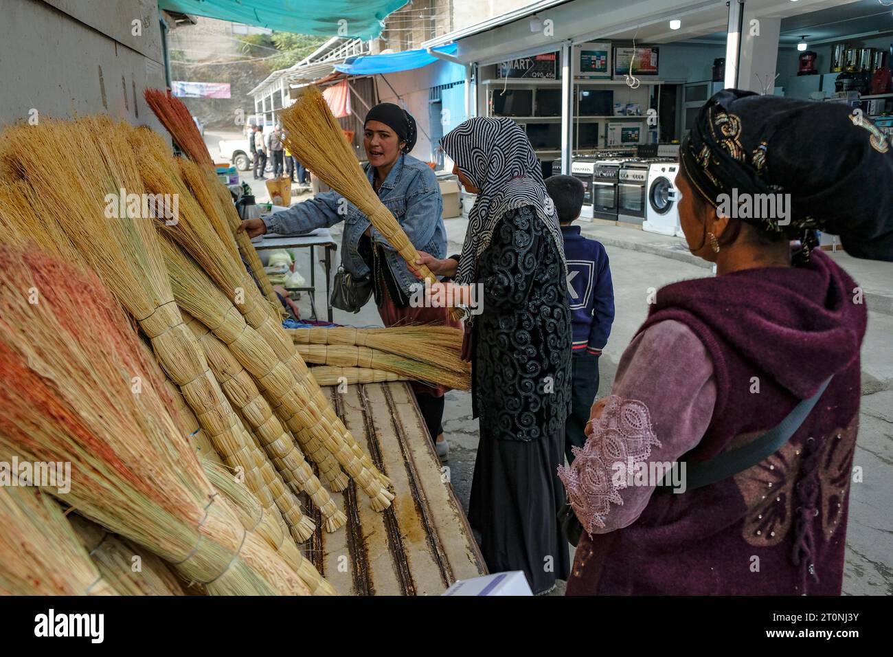 OSH, Kirgisistan - 8. Oktober 2023: Eine Frau, die Besen auf dem Jayma-Basar in Osh, Kirgisistan verkauft. Stockfoto