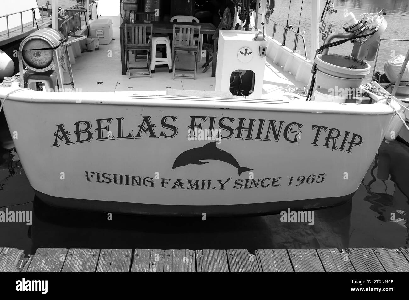 Hinterer Teil des Abelas Fishing Trip Boat, das Angeln und Schwimmen von Touristen anbietet und in Rhodos City's Kolona Hafen in Schwarz-weiß angedockt ist Stockfoto