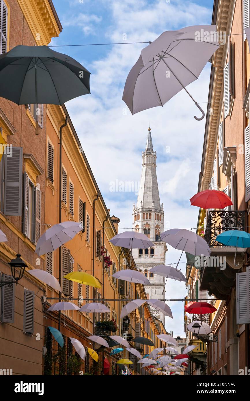 Bunte Regenschirme hängen in einer engen Straße, Ghirlandina, der Glockenturm der Kathedrale von Modena, im Hintergrund. Emilia-Romagna, Italien, Europa Stockfoto