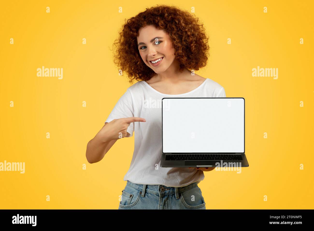 Lächelnde Teenager-Frau, die mit dem Finger auf leeren Laptop-Bildschirm zeigt Stockfoto