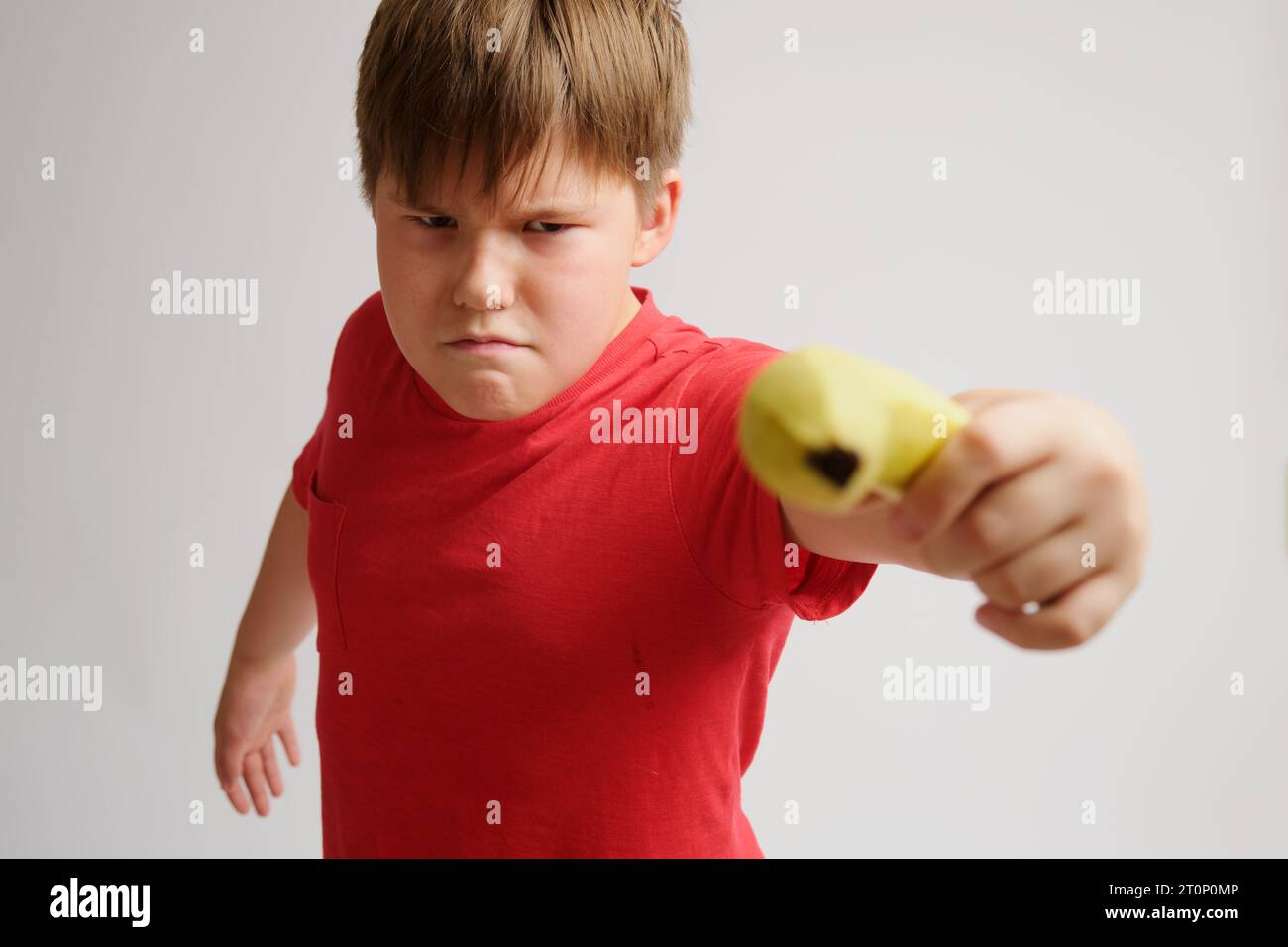 Junge, der mit einer gelben Banane auf grauem Hintergrund spielt Stockfoto