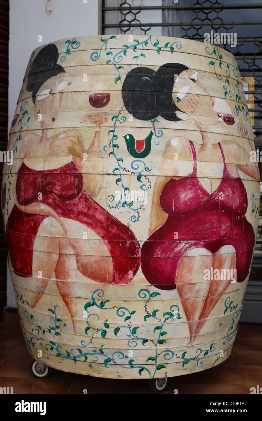 Zwei kleine Damen in roten Kleidern trinken Rotwein auf einem Weinfass gemalt Stockfoto