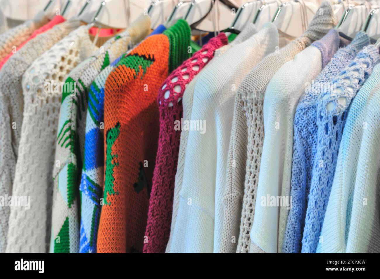 Mehrfarbige Familienbekleidung auf Kleiderbügeln im Geschäft Stockfoto