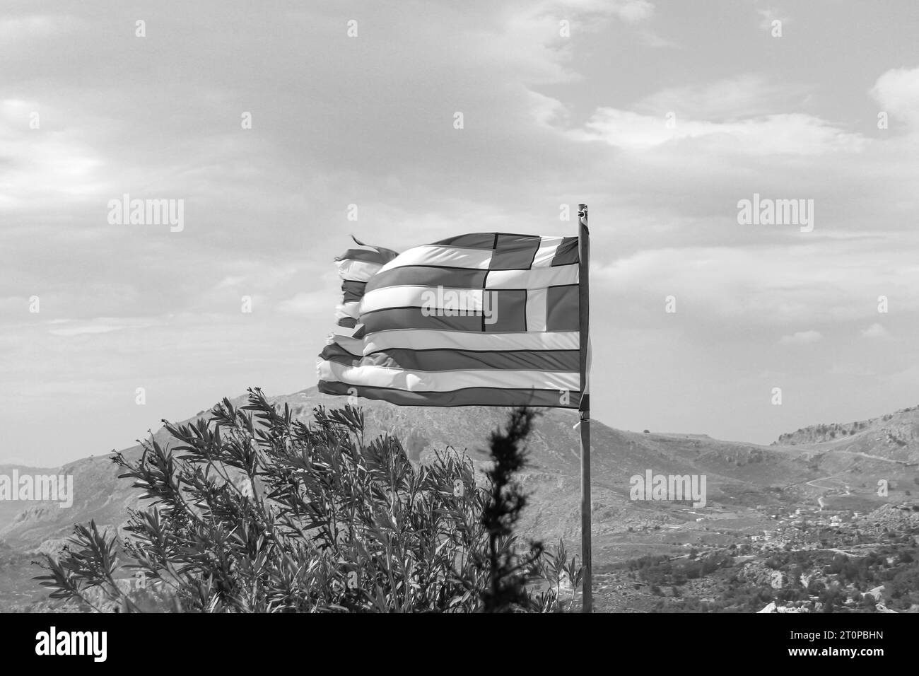 Griechische Nationalflagge oben auf dem Hügel des Klosters Tsambika auf Rhodos, Griechenland in Schwarz-weiß Stockfoto