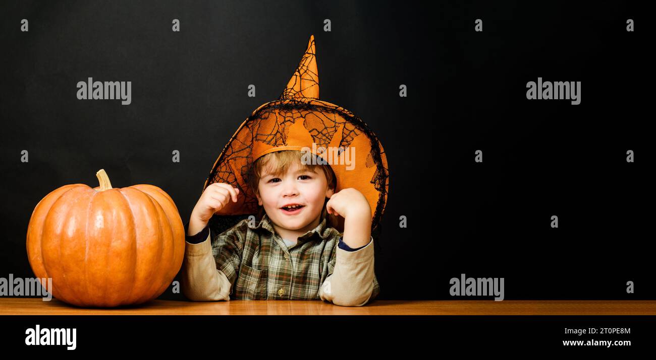 Glückliches Halloween-Kind in Hexenhut mit Jack-o-Laterne. Lächelnder kleiner Junge in Halloween-Kostüm und magischer Hut mit Kürbis für Halloween-Feiertage Stockfoto