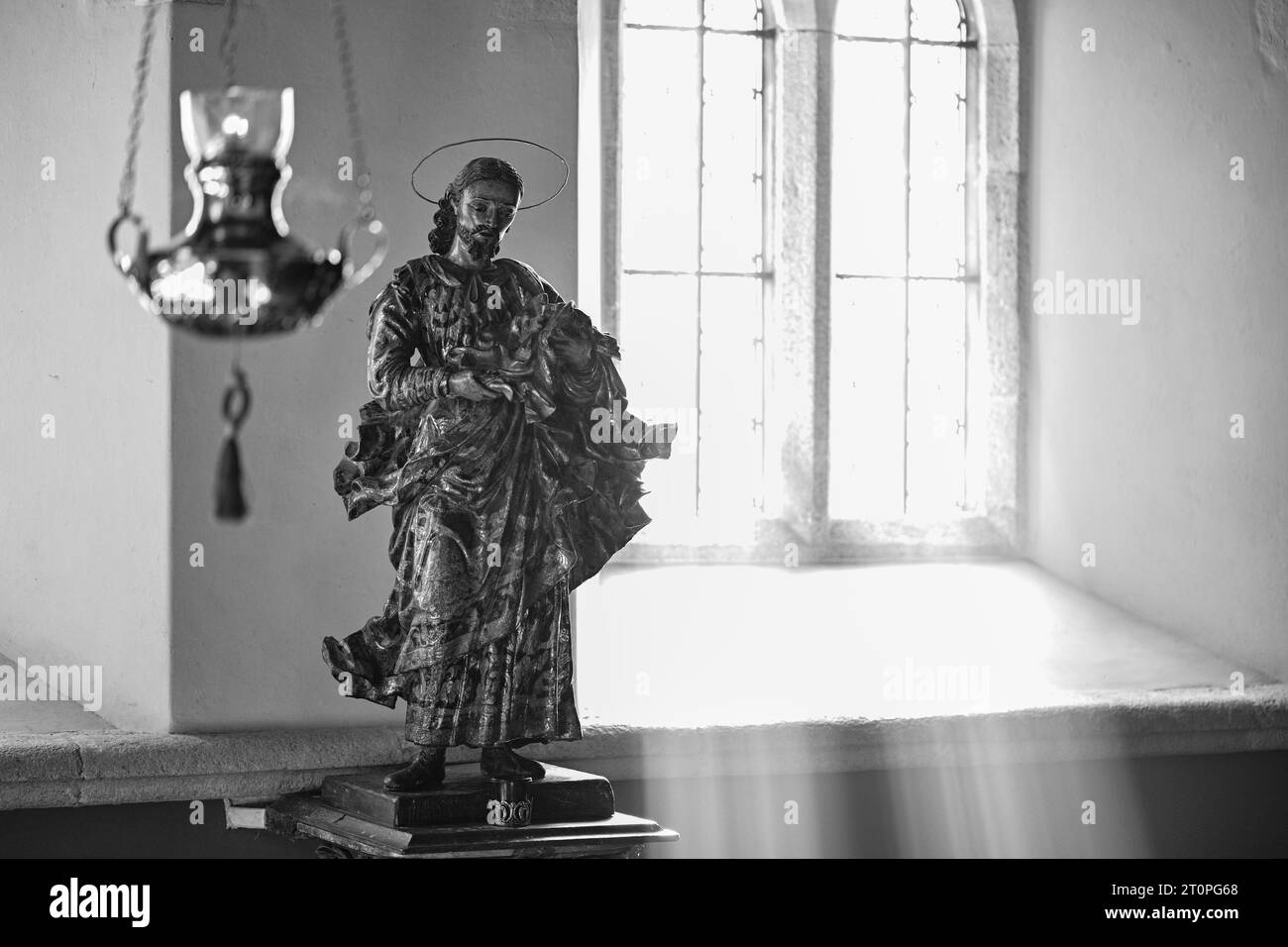 ST.HILARY KIRCHE SONNENLICHT STRÖMT DURCH DAS FENSTER UND BELEUCHTET DIE STATUE VON JESUS Stockfoto