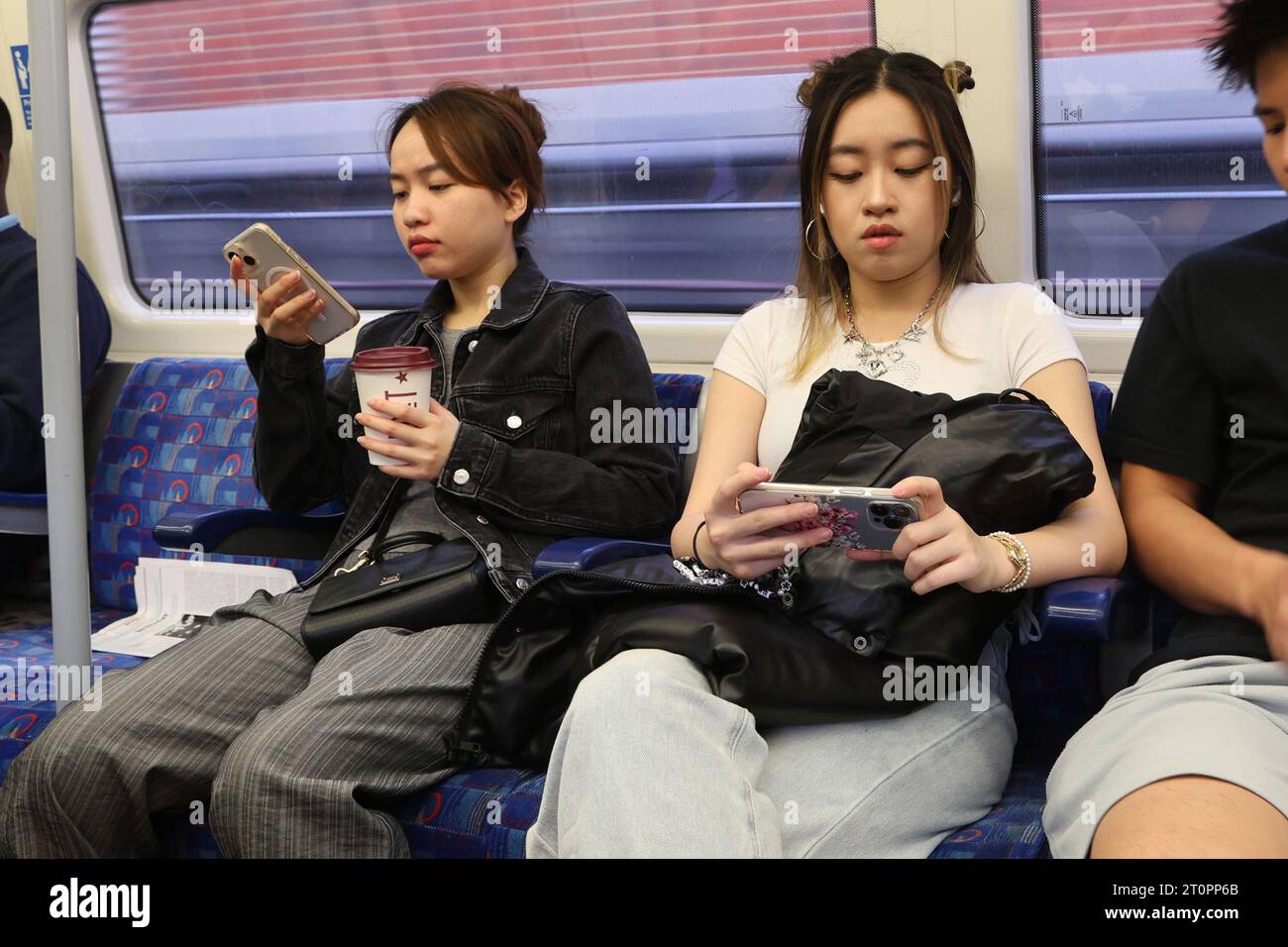 Frauen schauen auf ihre Smartphones, während sie in der Londoner U-Bahn reisen Stockfoto