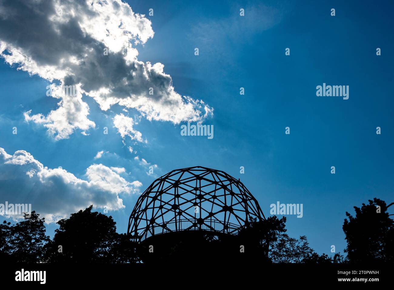 Silhouette eines kugelförmigen Aussichtsplatts aus Metall auf einem Hügel mit blauem Himmel und Wolken im Hintergrund Stockfoto