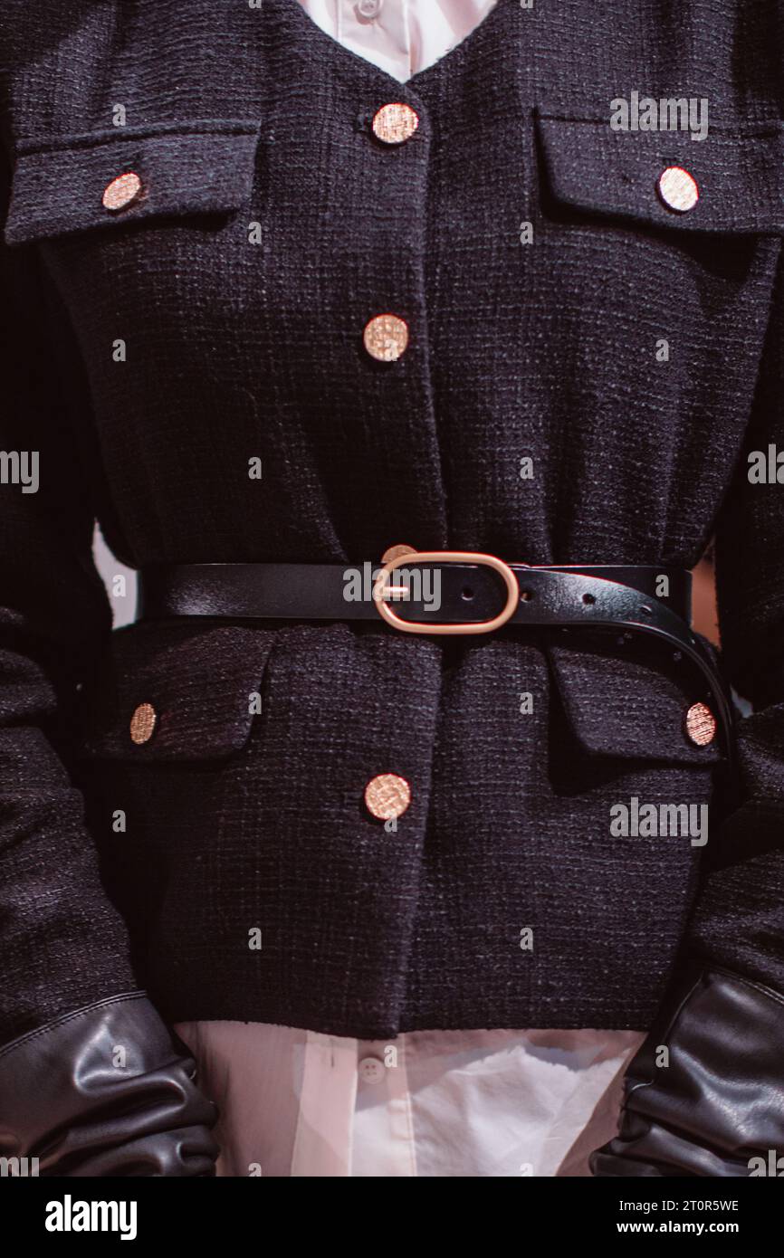 Modische Details einer eleganten schwarzen Jacke, eines Ledergürtels und goldener Knöpfe. Stockfoto