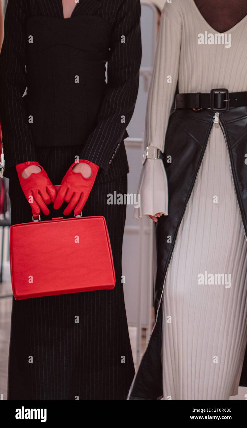 Modische Details eines gestrickten, warmweißen Kleides, roter Lederhandschuhe und Handtasche. Models posieren hinter der Bühne Stockfoto
