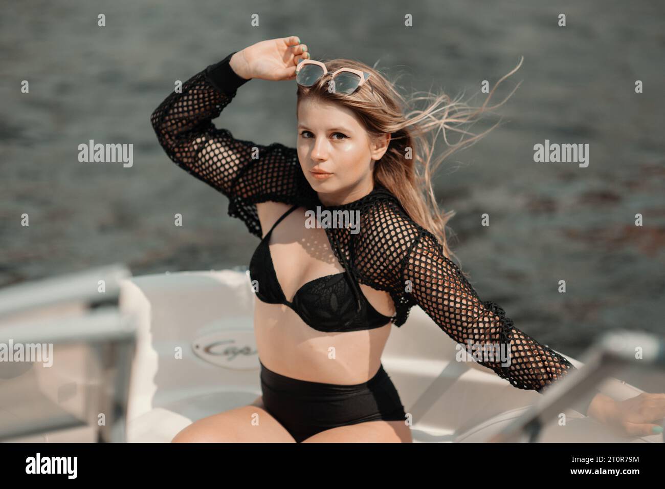 Porträt einer zärtlich lächelnden, sinnlichen jungen Frau, die einen Bikini in Vintage-Sonnenbrille trägt und sich an einem sonnigen Tag auf der Yacht entspannt Stockfoto