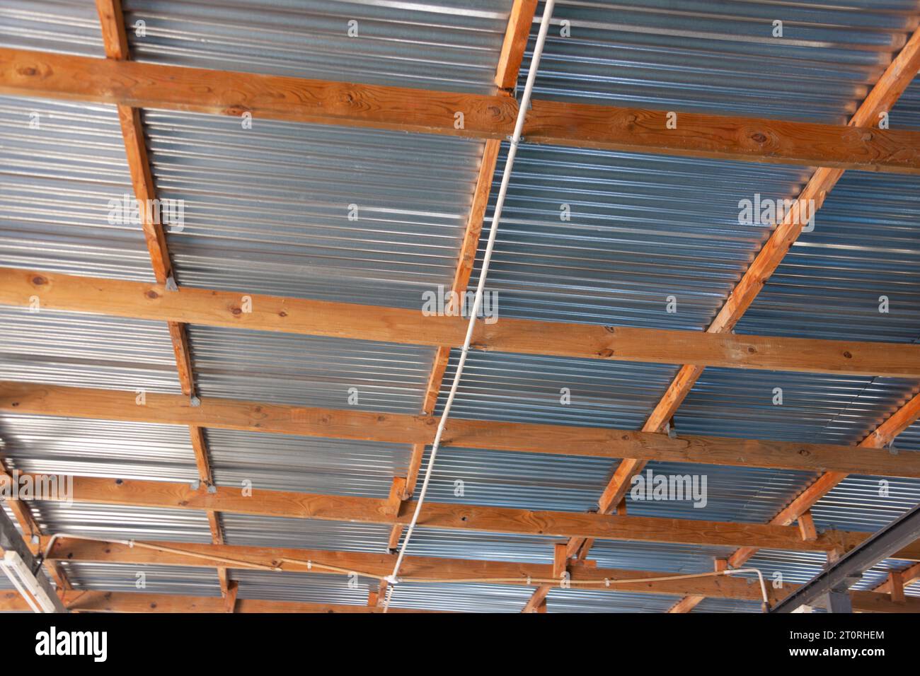 Wellblechdach und Holzbalken zur Unterstützung in Innenräumen Stockfoto
