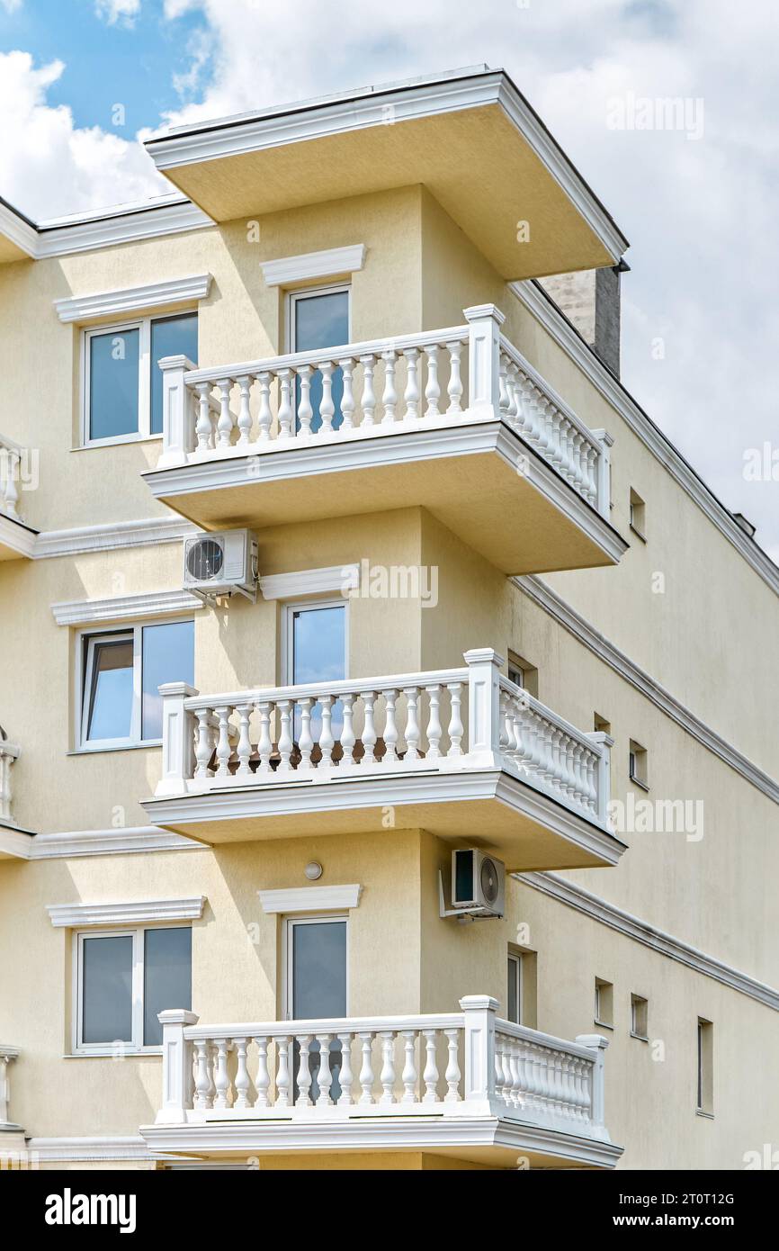 Gebäude mit mehrstöckigen Balkonen, dekoriert mit klassischen Betonzäunen mit Balustern. Eleganter äußerer Teil des Hotelkomplexes Stockfoto