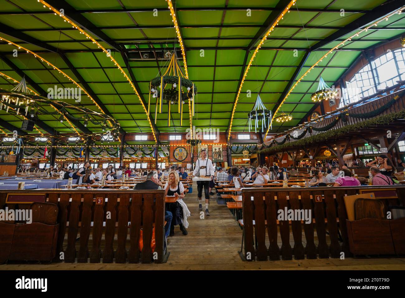 München, Deutschland, EU - 16. September 2023. Menschen, die trinken, essen im Augustiner Oktoberfest Bierzelt in München, tragen Dirndls und Lederhosen. Stockfoto