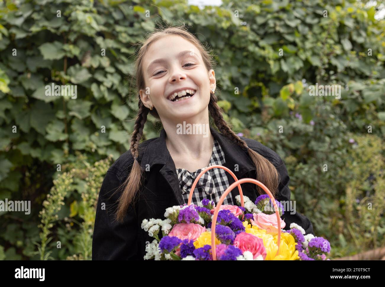 Porträt eines fröhlich lachenden Mädchens 7-8 Jahre alt mit einem Blumenstrauß in der Hand. Glückliche Kindheit, fröhliche emotionale Kinder, positives Kind. Stockfoto