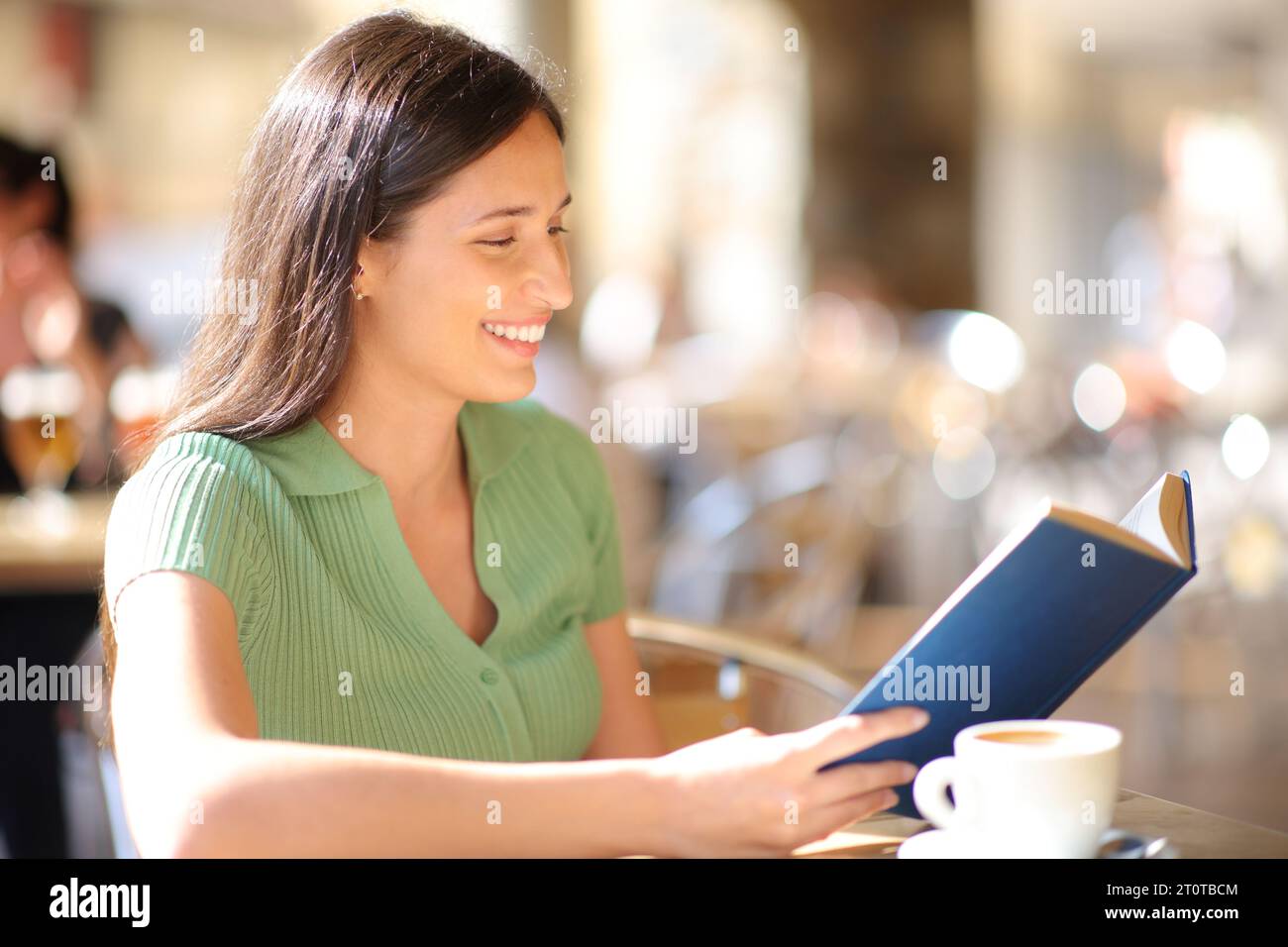 Happy Woman liest ein Buch auf einer Bar-Terrasse Stockfoto