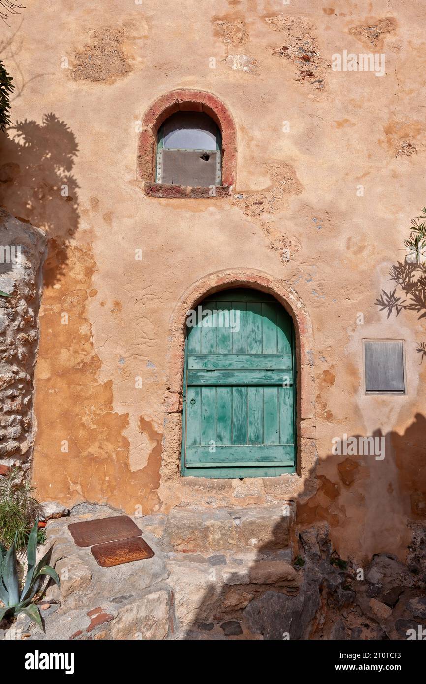 Traditionelles Haus mit ockerfarbenen Wänden und Holztür und -Fenster in der befestigten Stadt Monemvasia, einer Burgstadt der byzantinischen Zeit in Griechenland. Stockfoto