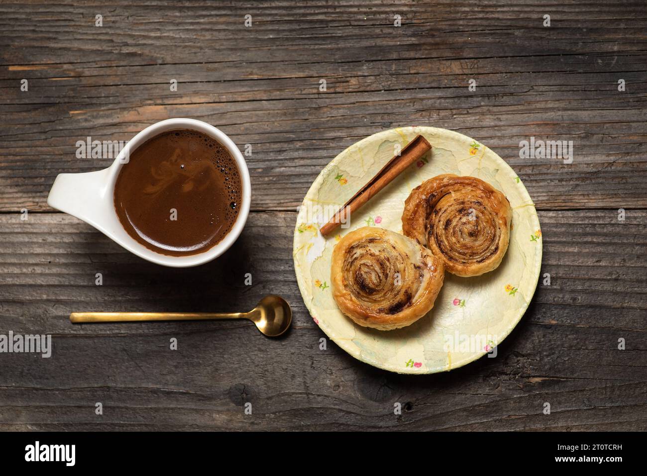 Frisch gebackene süße und knusprige Zimtrollen. Auf hölzernem Hintergrund, mit einer Tasse Kaffee Stockfoto